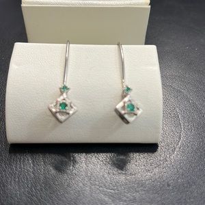White gold earring with emerald accents.